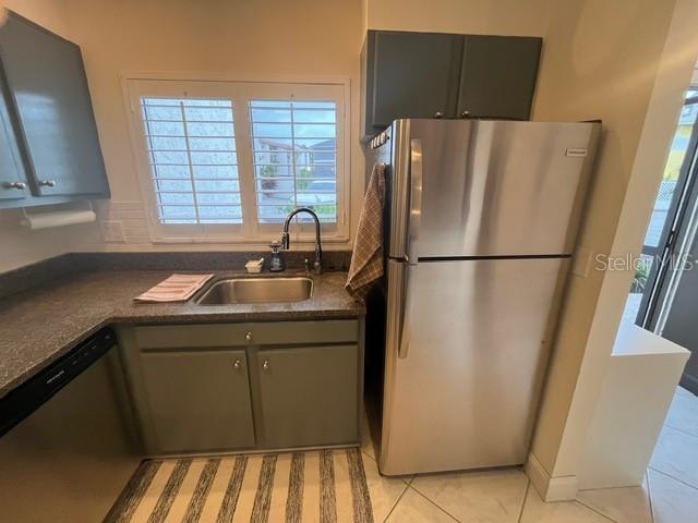 A kitchen features gray cabinets, a stainless steel refrigerator, and a window above the sink — 1614 STICKNEY POINT ROAD UNIT 102, SARASOTA, FL