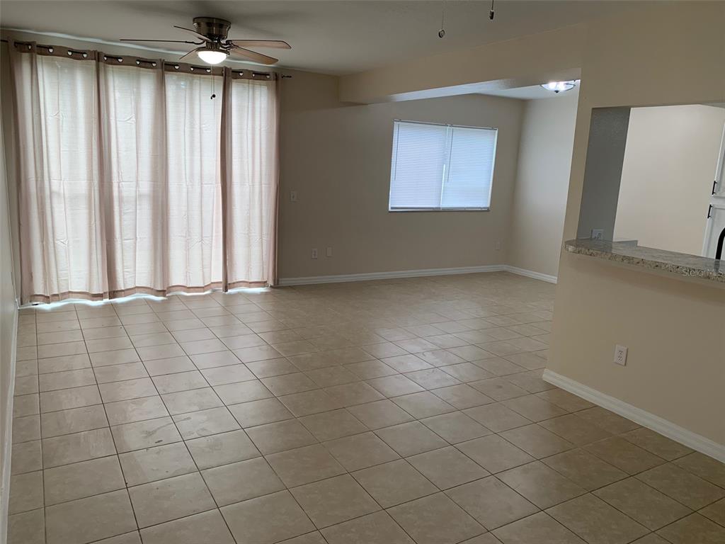 An open-concept living area features beige tile flooring, neutral walls, and a sliding glass door — 761 CARIBBEAN DRIVE, DAVENPORT, FL