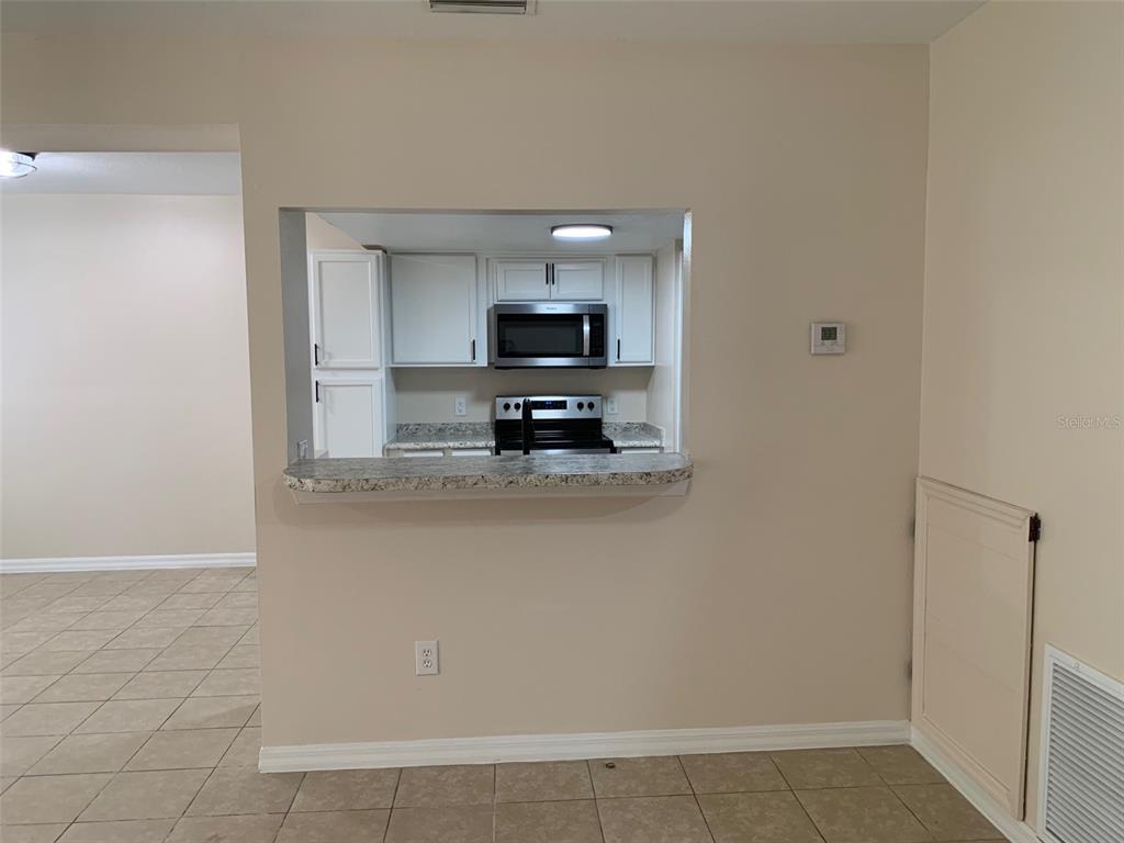 A kitchen view through a pass-through window with a breakfast bar and tile flooring — 761 CARIBBEAN DRIVE, DAVENPORT, FL