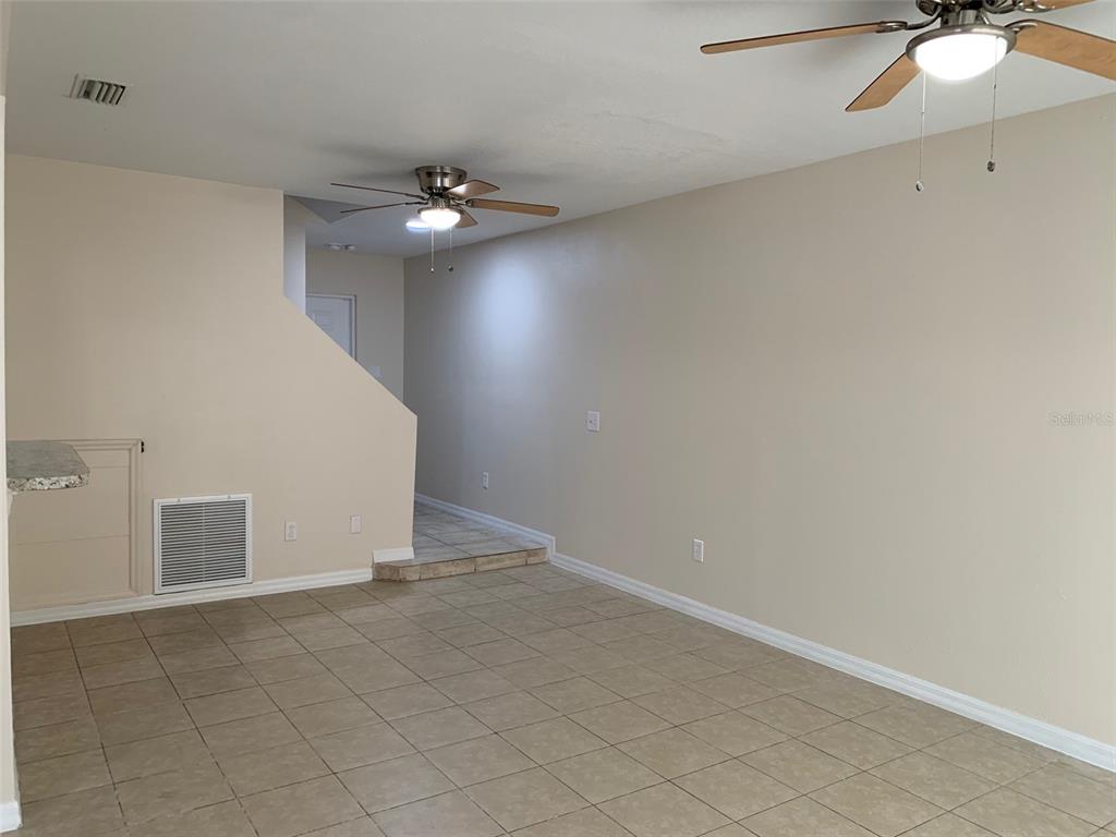 An interior view of a living area with tile flooring, two ceiling fans, and stairs — 761 CARIBBEAN DRIVE, DAVENPORT, FL