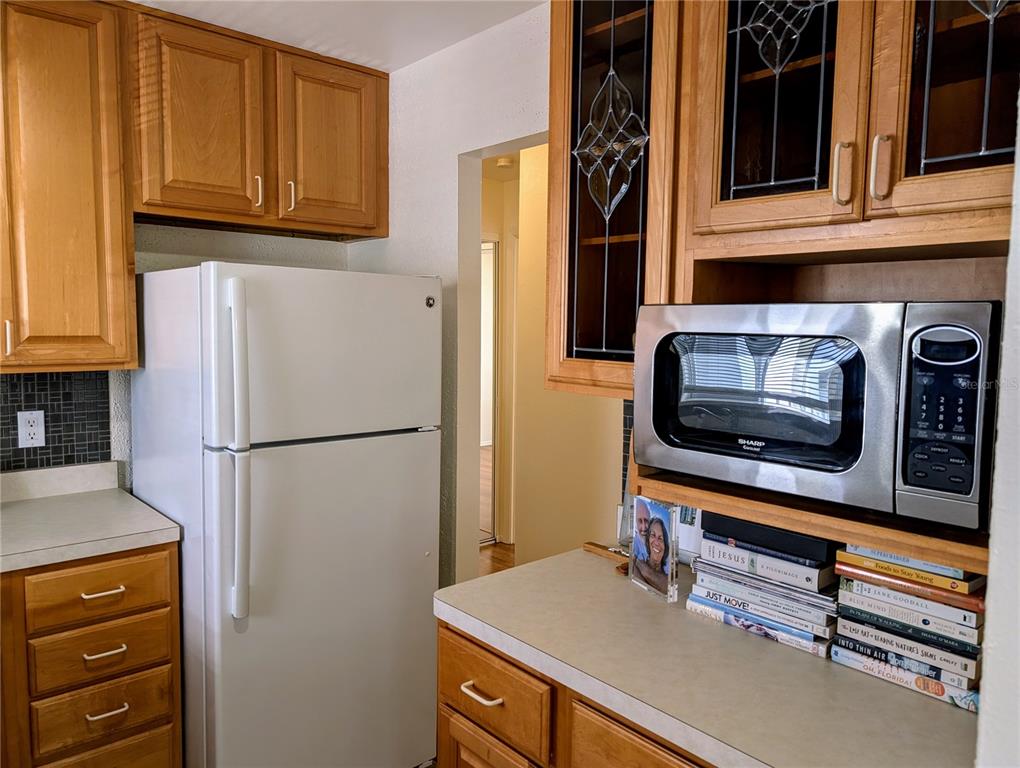 A kitchen features wood cabinets, a white refrigerator, a stainless steel microwave, and laminate countertops — 1545 PLEASANT ROAD UNIT H-23, BRADENTON, FL