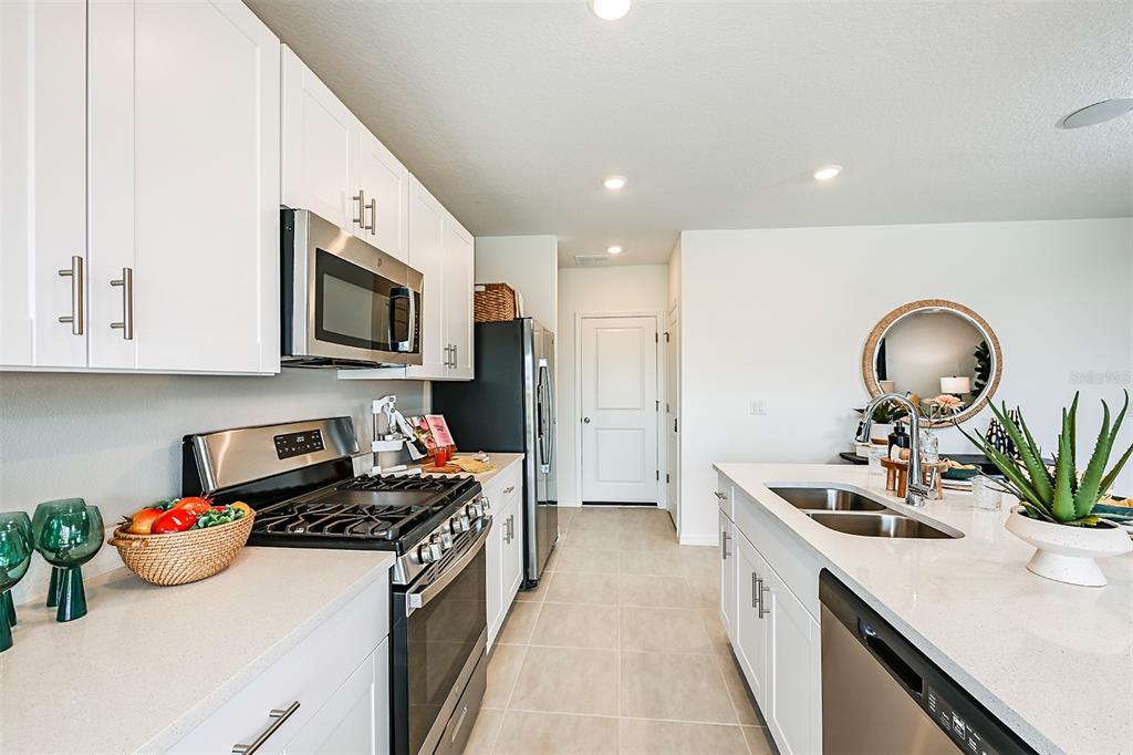 A modern kitchen features white cabinets, stainless steel appliances, and a central island with sink — 7677 GEMSTONE STREET, GROVELAND, FL