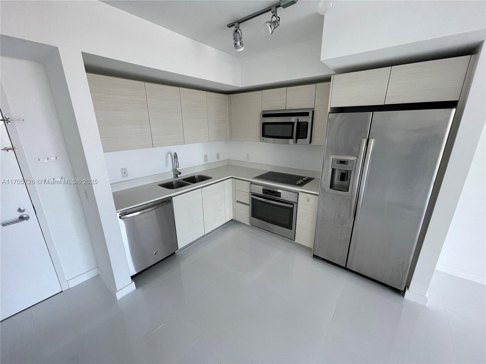 A modern kitchen features light wood cabinets, stainless steel appliances, and white countertops — 4250 Biscayne Blvd # 1104, Miami FL 33137, MIAMI, FL