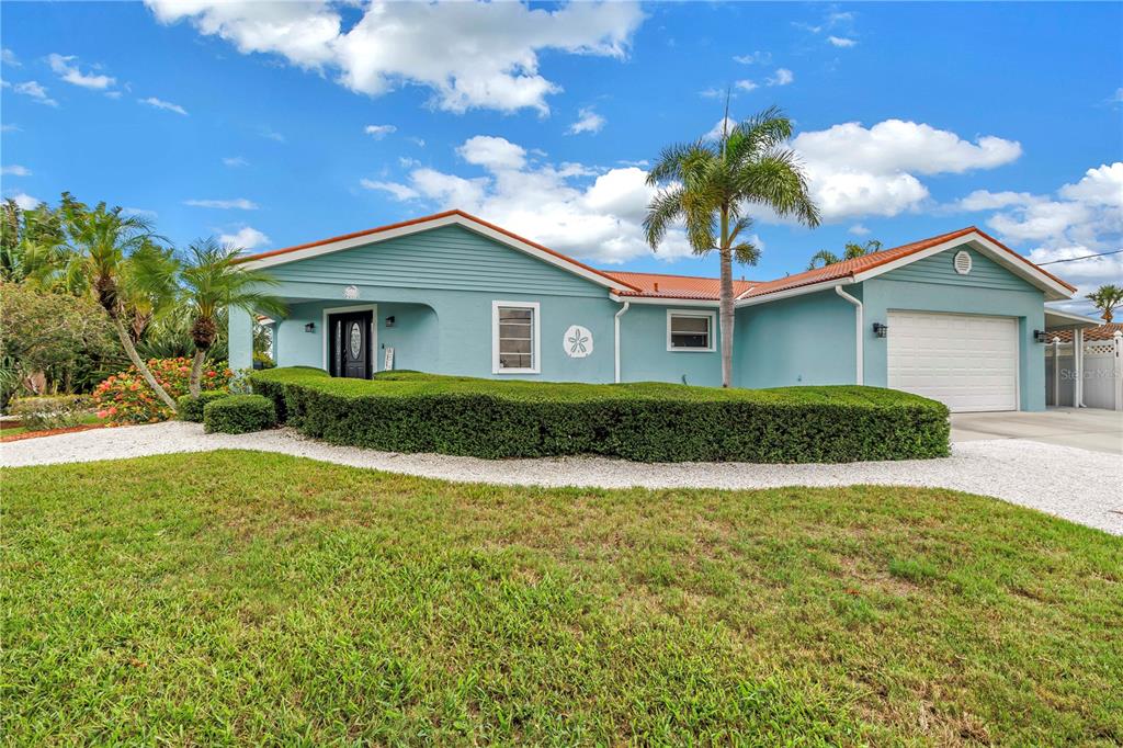 A light blue single-story house with a red tile roof and a manicured hedge — 4911 PALMETTO POINT DRIVE, PALMETTO, FL