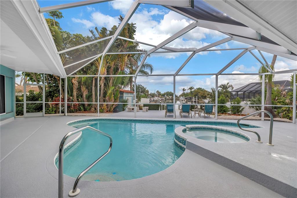 A screened-in pool and spa area with a view of a canal and boats — 4911 PALMETTO POINT DRIVE, PALMETTO, FL