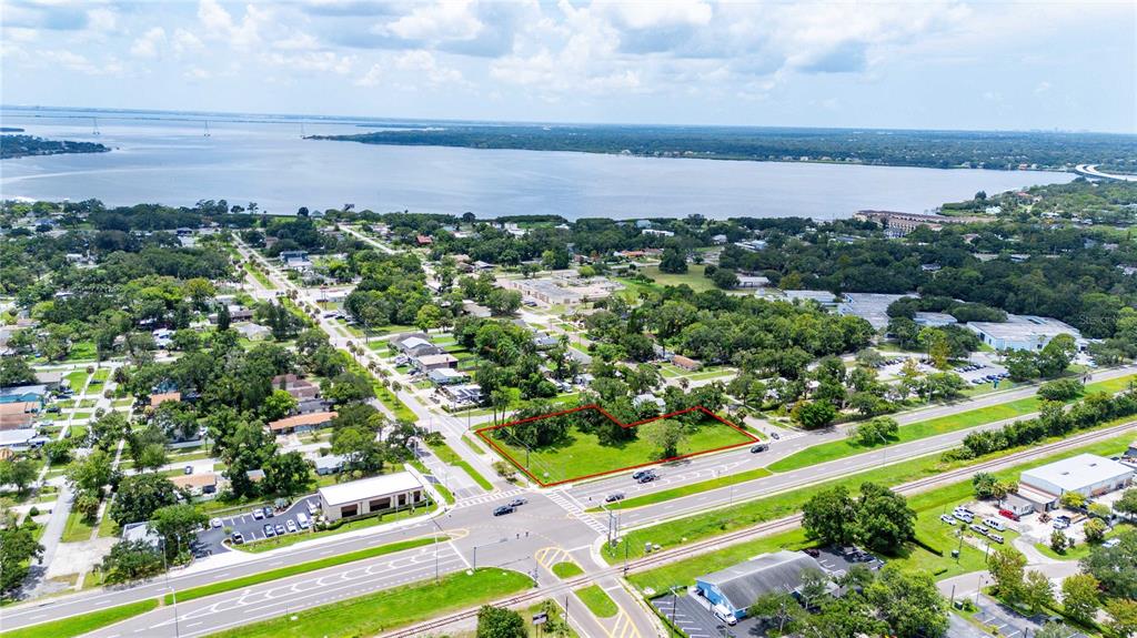 An aerial view shows a vacant, grass-covered lot outlined in red near a coastal road — 205 CHESTNUT STREET, OLDSMAR, FL