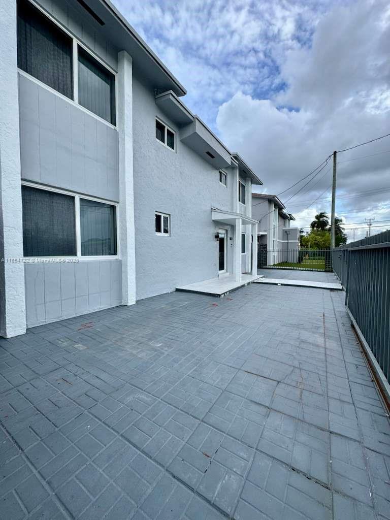A paved driveway leads to the side entrance of a two-story light gray residential building — 1671 SW 29th Ave, Miami FL 33145, MIAMI, FL