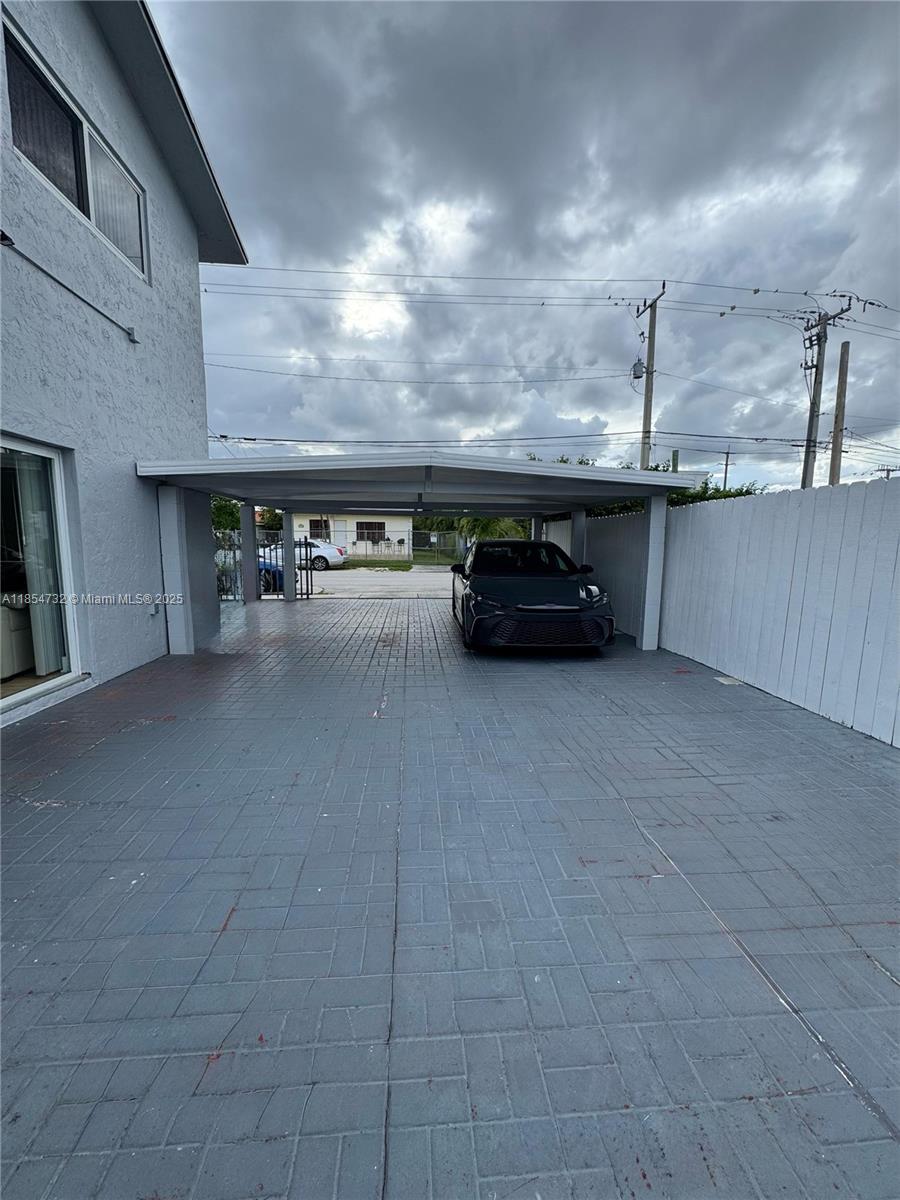 A paved driveway features a covered carport with a dark car parked underneath — 1671 SW 29th Ave, Miami FL 33145, MIAMI, FL
