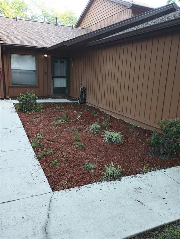 A brown house exterior features a front entrance and a mulched garden bed — 2701 NE 10TH STREET UNIT 802, OCALA, FL