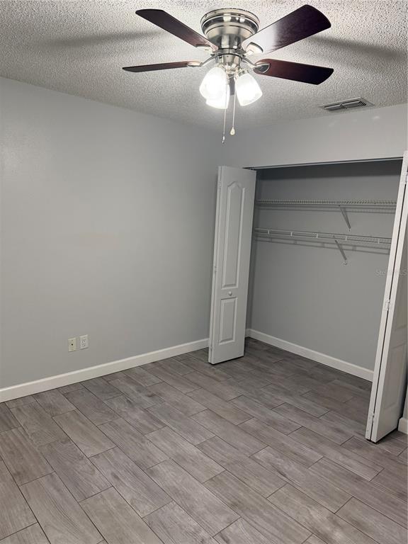 A bedroom with gray walls, wood-look tile flooring, a ceiling fan, and a closet — 2701 NE 10TH STREET UNIT 802, OCALA, FL