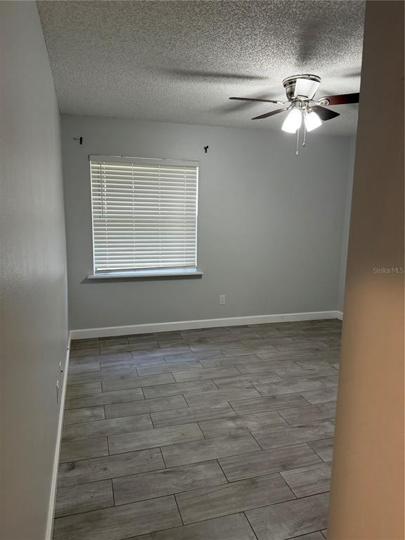 A bedroom with gray walls, wood-look tile flooring, a ceiling fan, and a window with blinds — 2701 NE 10TH STREET UNIT 802, OCALA, FL