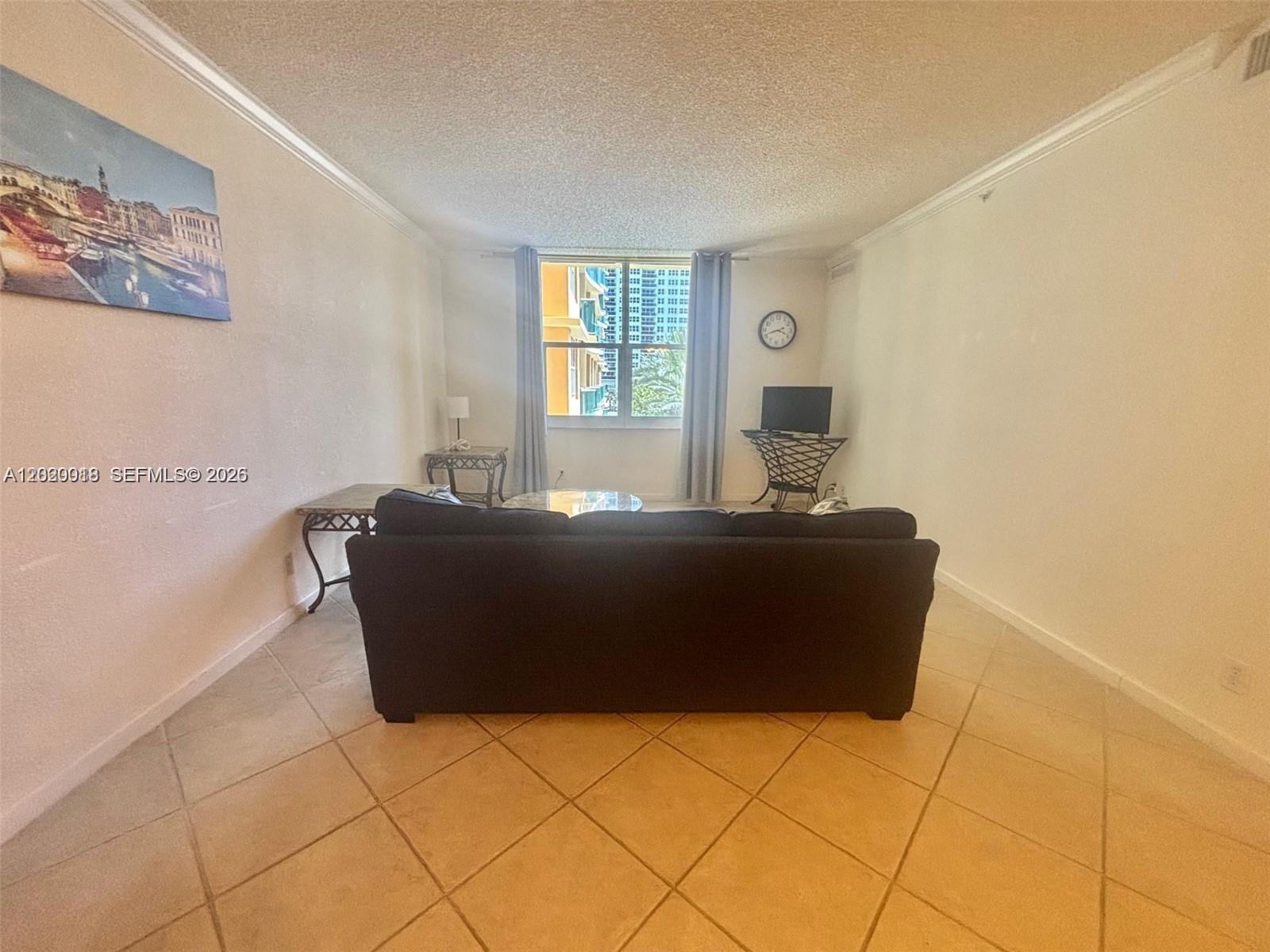 A living room features a dark sofa, tile flooring, and a window with curtains — 2501 S Ocean Dr # 433, Hollywood FL 33019, HOLLYWOOD, FL
