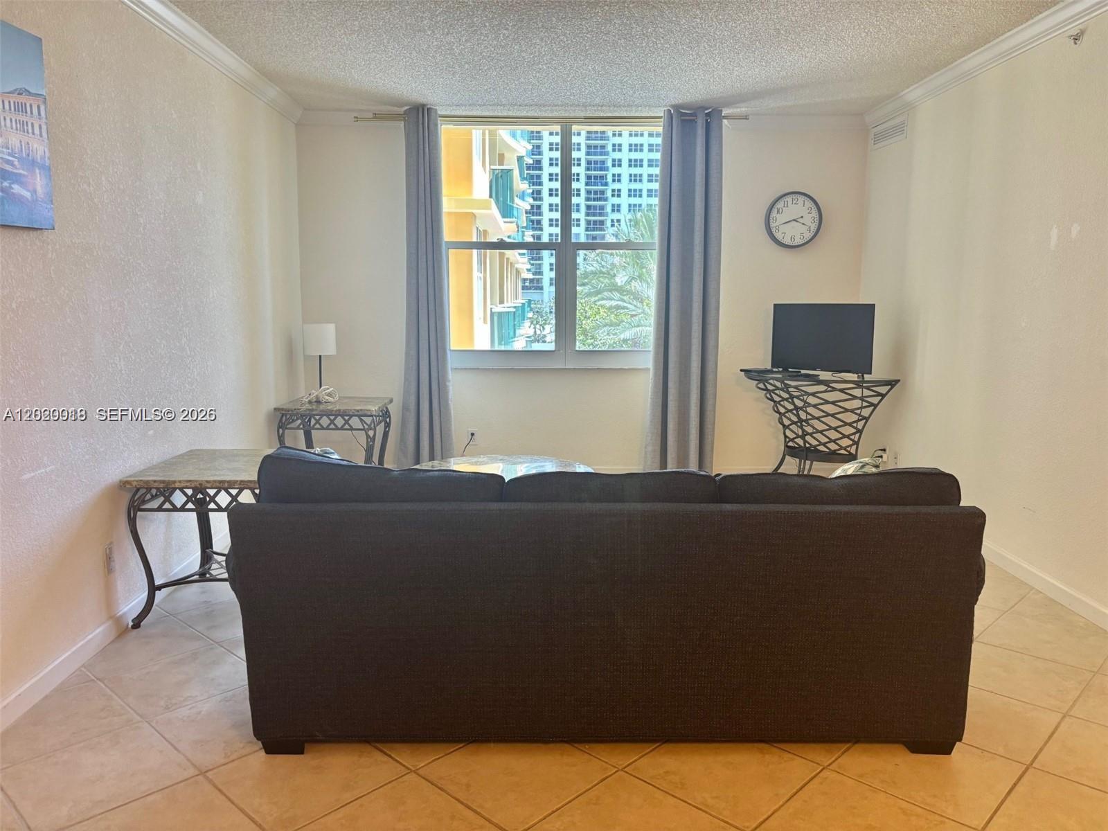 A living room features a dark sofa, two metal-framed tables, a television, and a window — 2501 S Ocean Dr # 433, Hollywood FL 33019, HOLLYWOOD, FL