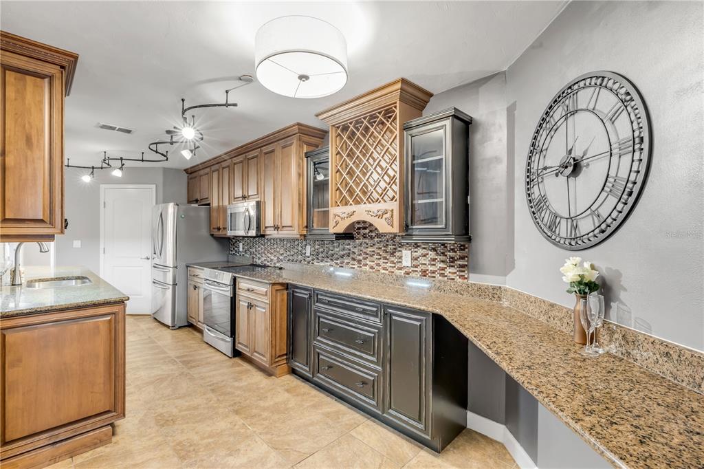 A kitchen features wood and dark cabinets, granite countertops, a wine rack, and a wall clock — 424 LUNA BELLA LANE UNIT 231, NEW SMYRNA BEACH, FL