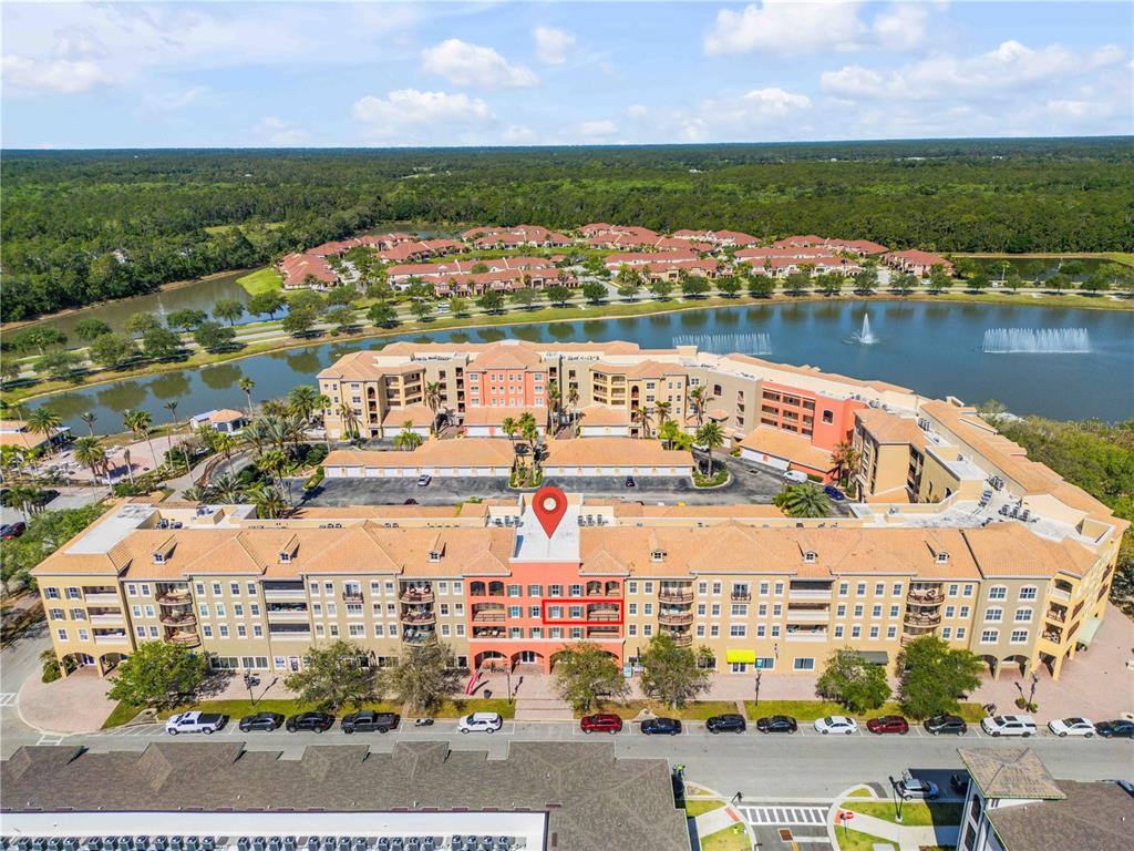 An aerial view shows a multi-story apartment complex with a red-outlined balcony and parking — 424 LUNA BELLA LANE UNIT 231, NEW SMYRNA BEACH, FL