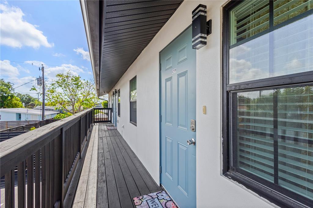 An exterior view of a second-story balcony with a blue door and dark wood railing — 4219 60TH STREET COURT W, BRADENTON, FL