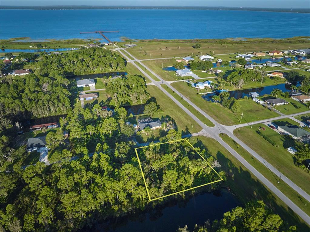 An aerial view shows a wooded, rectangular lot outlined in yellow near a waterfront area — 2 AMARYLLIS DRIVE, INDIAN LAKE ESTATES, FL