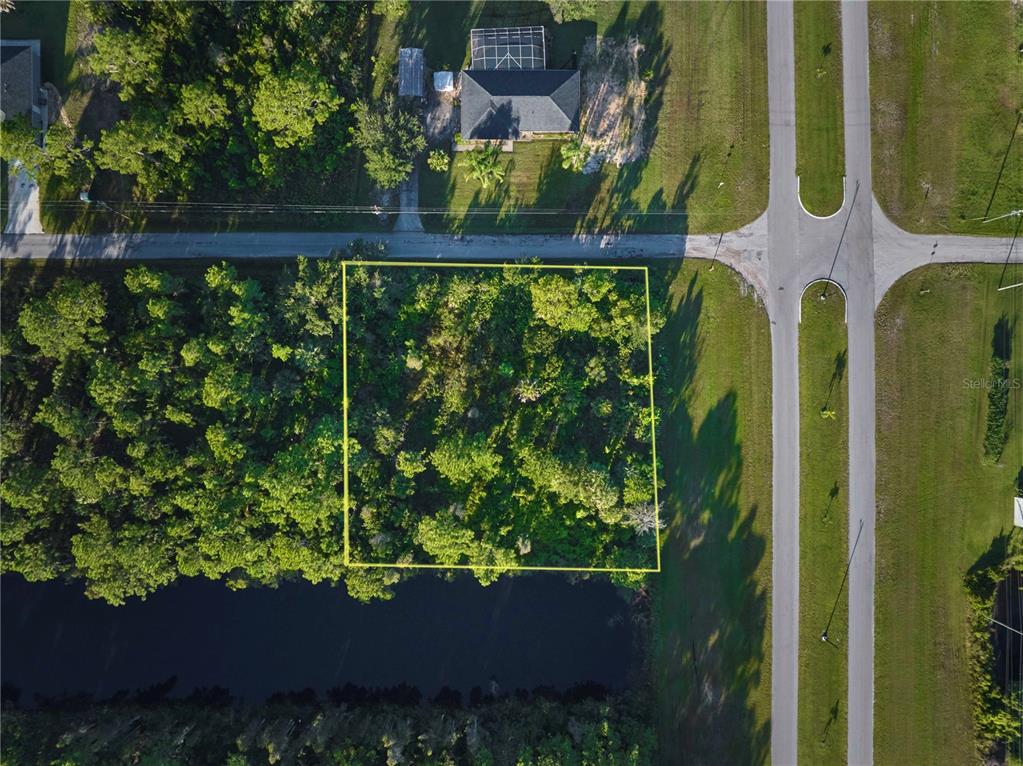 An aerial view shows a rectangular, wooded vacant lot bordered by a road and canal — 2 AMARYLLIS DRIVE, INDIAN LAKE ESTATES, FL