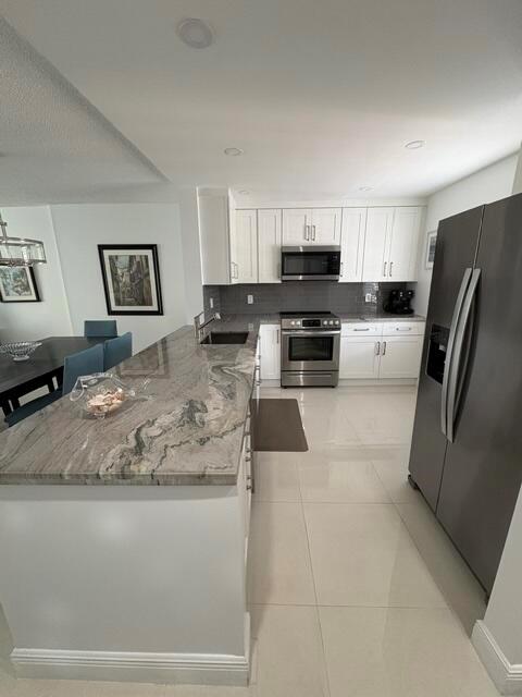 A modern kitchen features white cabinetry, stainless steel appliances, and a large stone-topped island — 424 SE 10th Street # 203, Dania Beach FL 33004, DANIA BEACH, FL