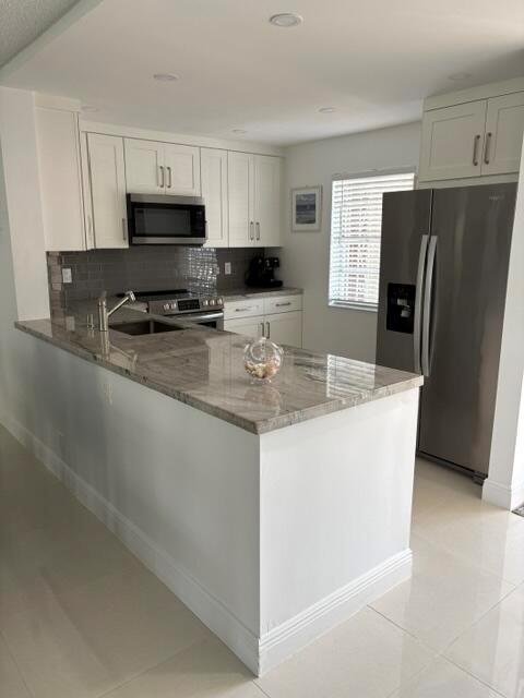 A modern kitchen features white cabinets, granite countertops, stainless steel appliances, and a breakfast bar — 424 SE 10th Street # 203, Dania Beach FL 33004, DANIA BEACH, FL