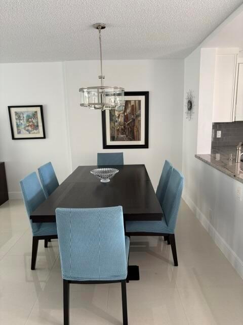 A dining room features a dark wood table, blue chairs, and a modern pendant light — 424 SE 10th Street # 203, Dania Beach FL 33004, DANIA BEACH, FL