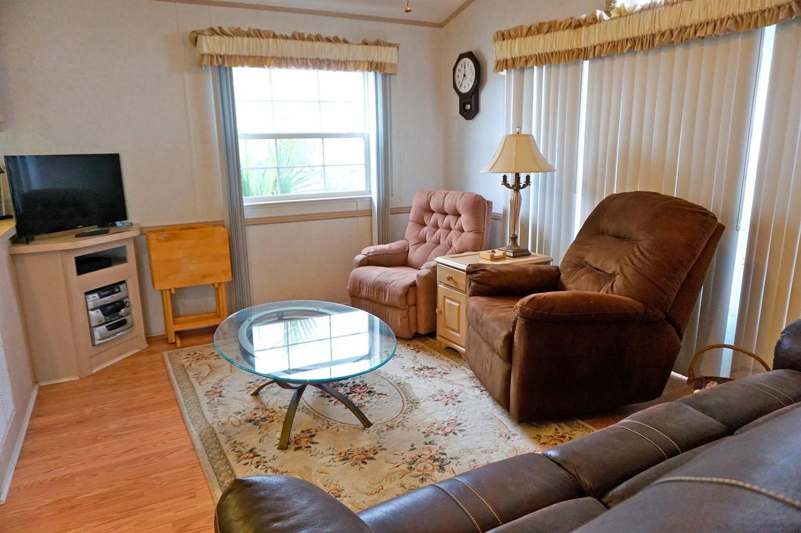 A living room features a glass coffee table, two recliners, a sofa, and a television — 10725 S Ocean Drive # 265, Jensen Beach FL 34957, JENSEN BEACH, FL