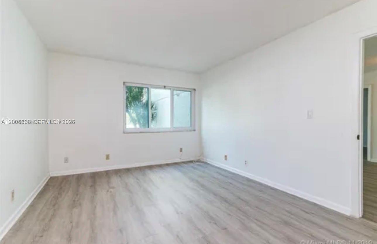 An empty bedroom features white walls, light wood-look flooring, and a single window — 100 Lakeview Dr # 112, Weston FL 33326, WESTON, FL
