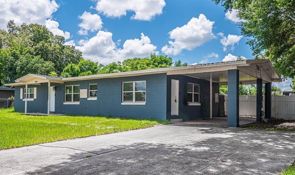 A single-story blue concrete block house features a front carport and a concrete driveway — 2414 AVENUE A TERRACE NW, WINTER HAVEN, FL