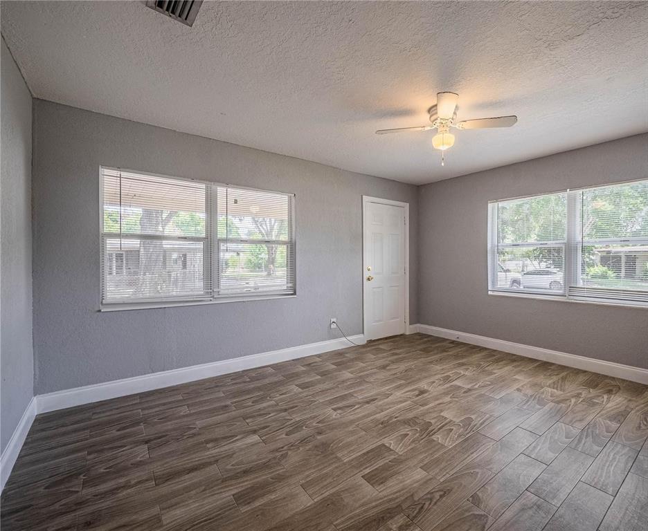 An empty room with gray walls, wood-look tile flooring, a ceiling fan, and two windows — 2414 AVENUE A TERRACE NW, WINTER HAVEN, FL