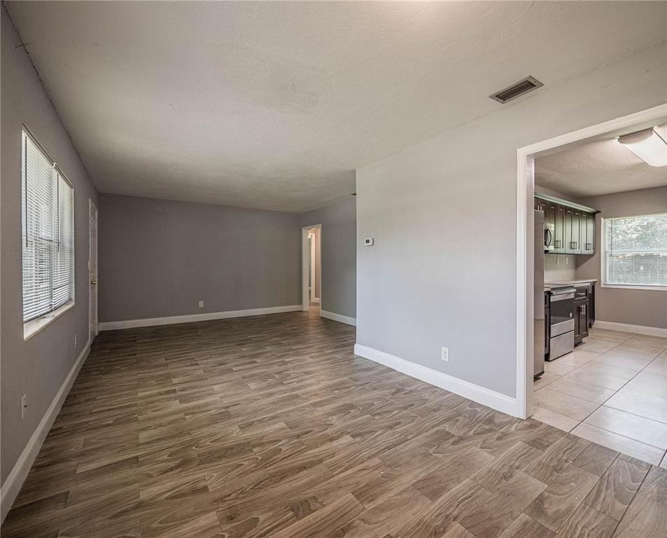 A living room with gray walls and wood-look flooring leads into a tiled kitchen — 2414 AVENUE A TERRACE NW, WINTER HAVEN, FL