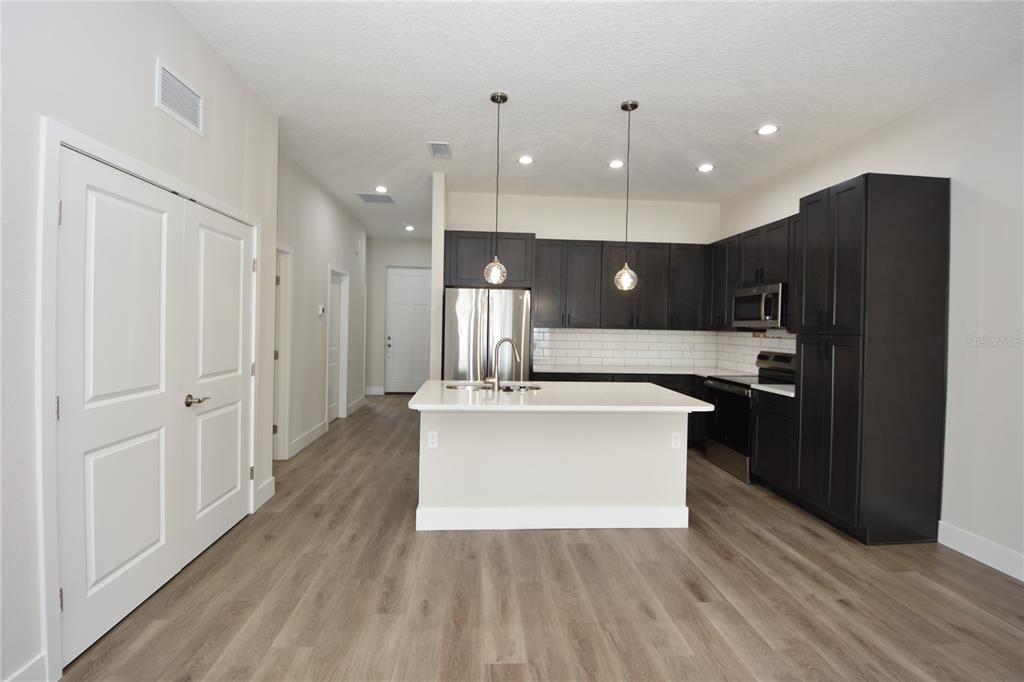 A kitchen features dark cabinets, a white island, and light wood-look flooring — 5 SETON COURT UNIT B, PALM COAST, FL