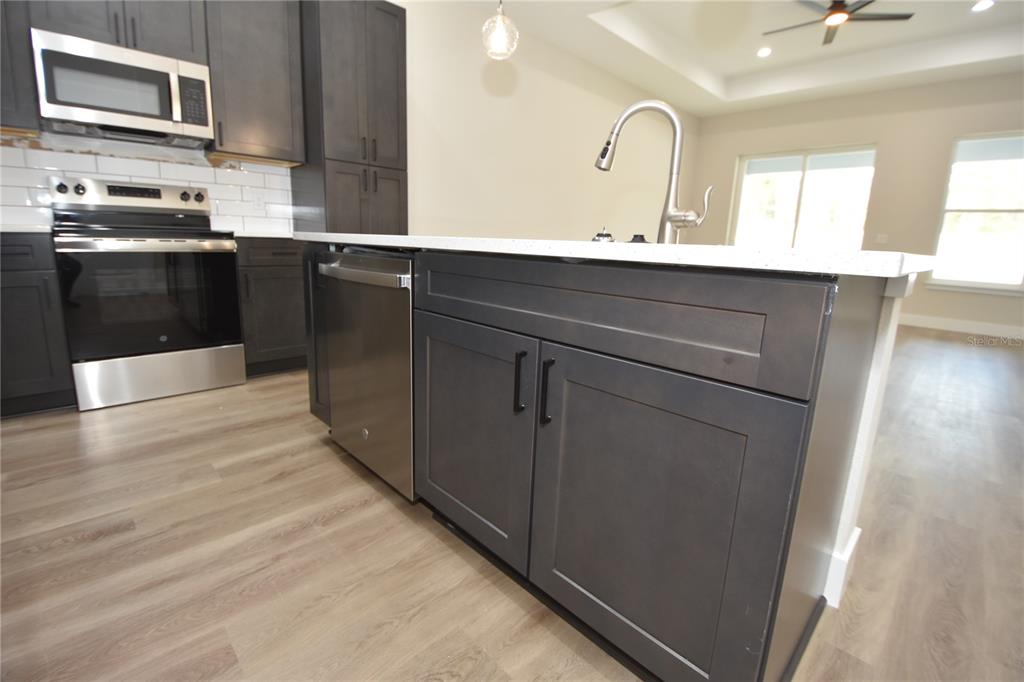 A kitchen features dark gray cabinets, stainless steel appliances, and a white quartz island countertop — 5 SETON COURT UNIT B, PALM COAST, FL