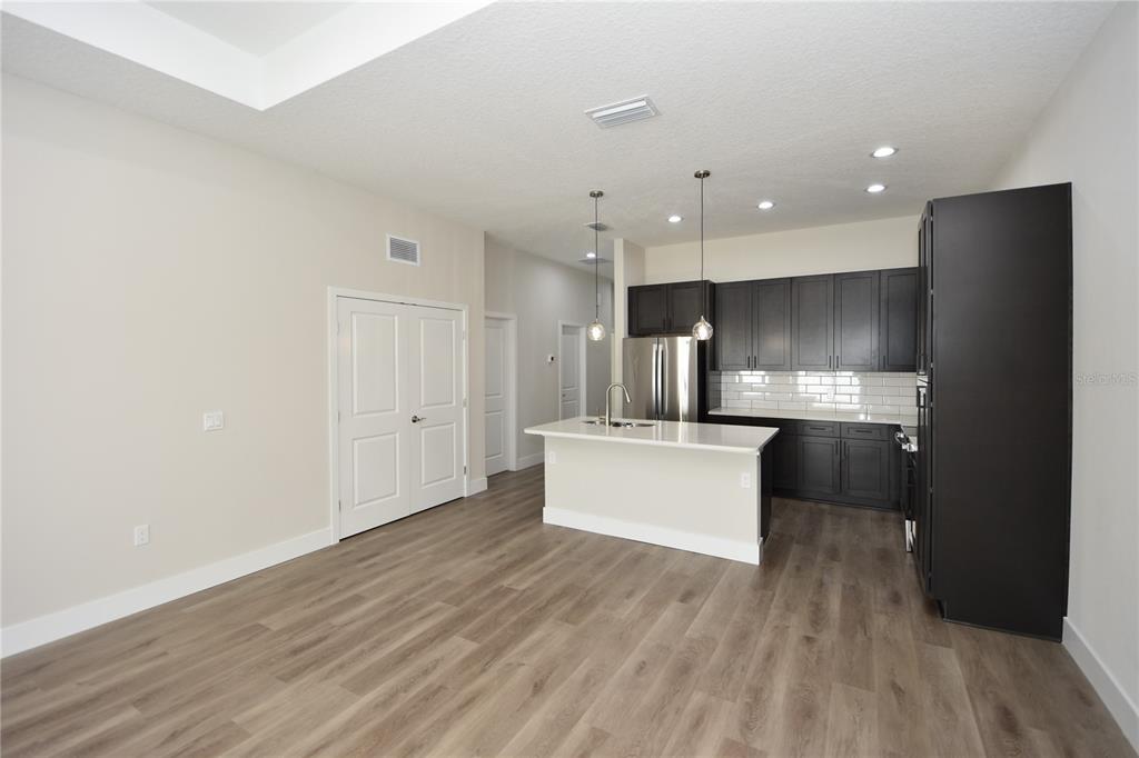 A kitchen with dark cabinets, a white island, and light wood-look flooring — 5 SETON COURT UNIT B, PALM COAST, FL