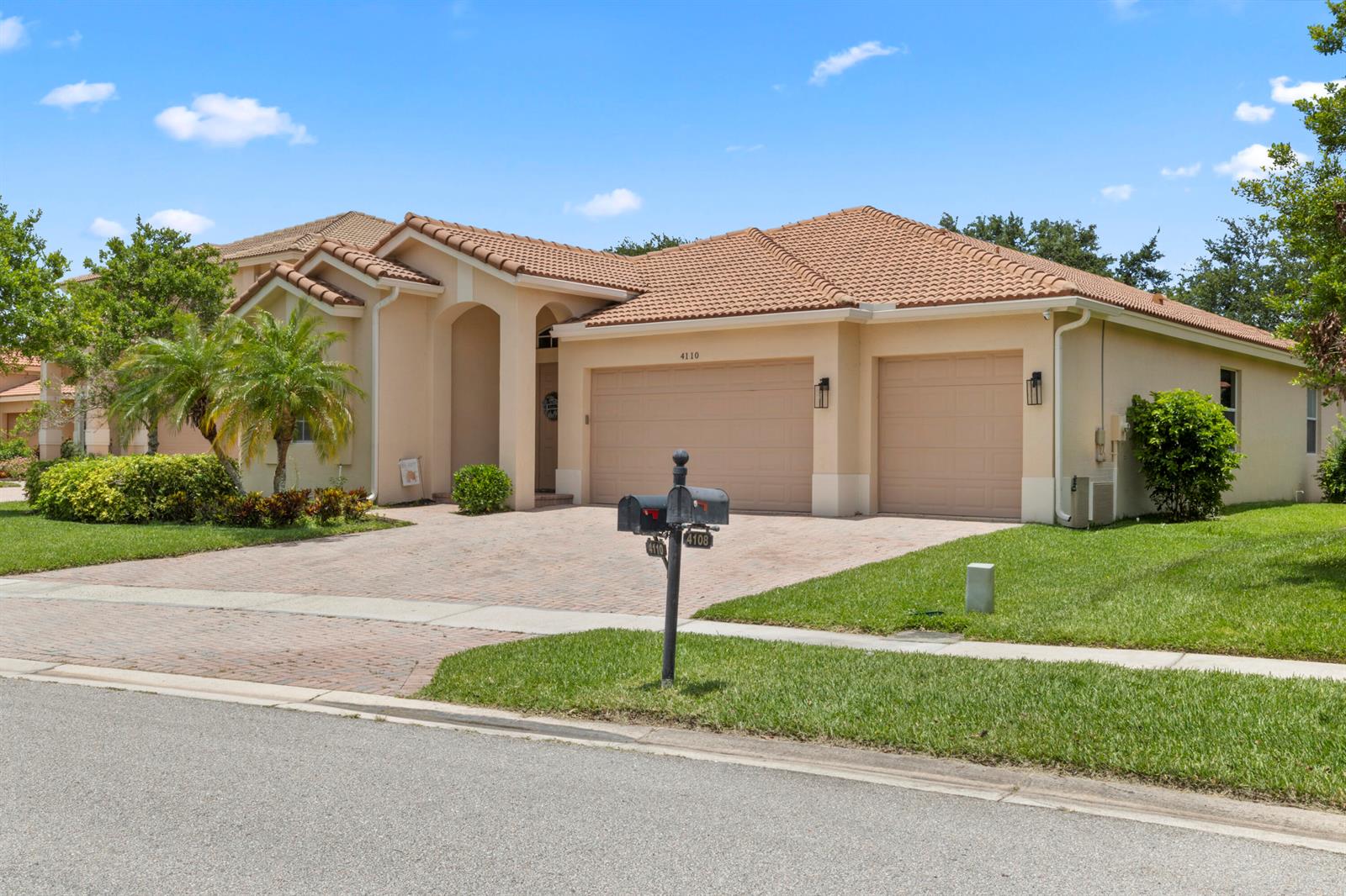 A tan single-story house with a tiled roof and a three-car garage — 4110 Silverstone Drive, Fort Pierce FL 34947, FORT PIERCE, FL