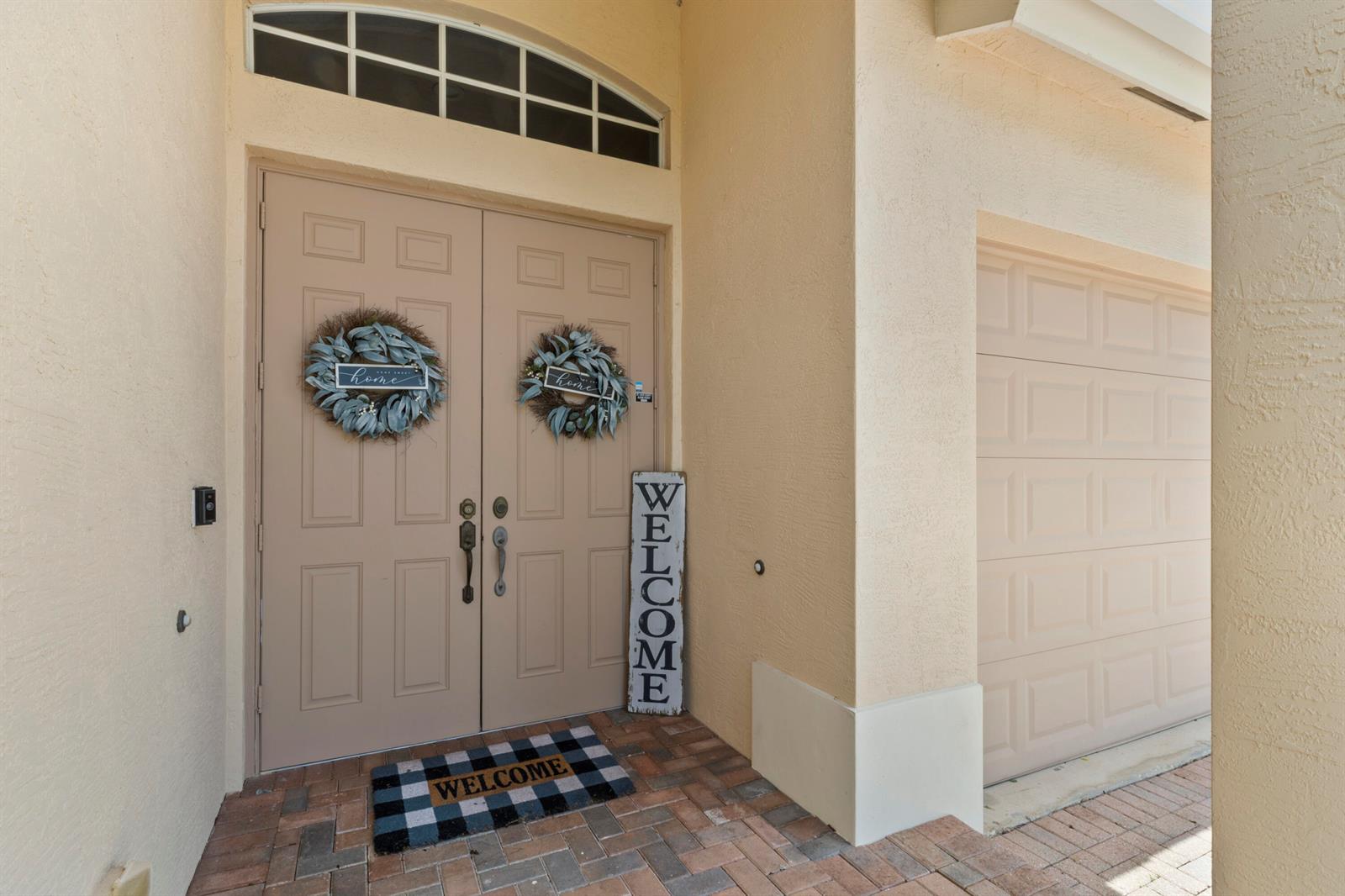 A front entryway features double doors with wreaths, a welcome sign, and a checkered mat — 4110 Silverstone Drive, Fort Pierce FL 34947, FORT PIERCE, FL