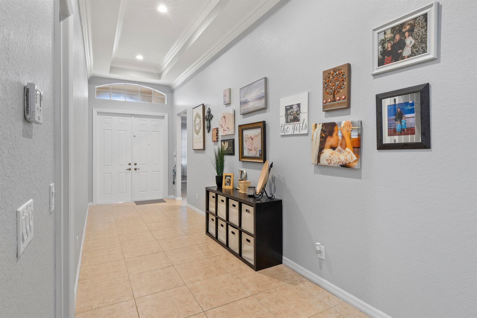 A bright entryway features tile flooring, a tray ceiling, and a gallery wall of photos — 4110 Silverstone Drive, Fort Pierce FL 34947, FORT PIERCE, FL