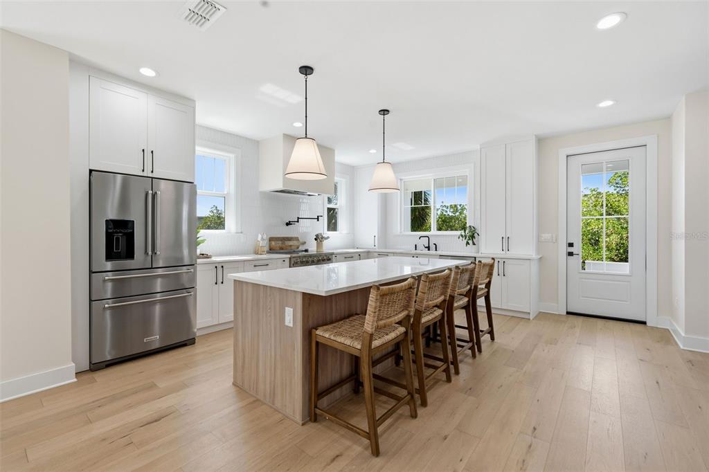 An open-concept kitchen and dining area features light wood floors, white cabinetry, and a beverage refrigerator — 1811 BAYOU GRANDE BOULEVARD NE, ST PETERSBURG, FL