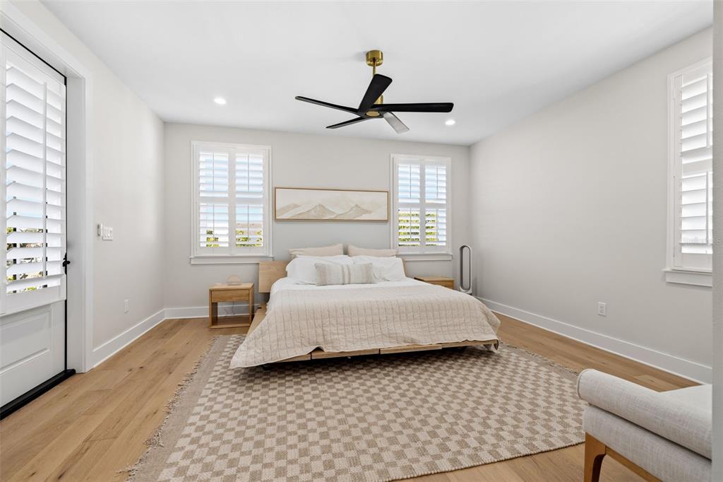A modern open-concept kitchen features a large island, light wood flooring, and white cabinetry — 1811 BAYOU GRANDE BOULEVARD NE, ST PETERSBURG, FL