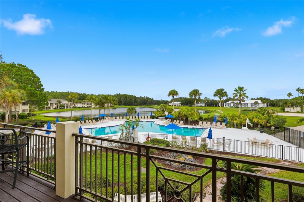 An elevated balcony view overlooks a swimming pool, a small lake, and surrounding residential buildings — 29130 BAY HOLLOW DRIVE UNIT 3314, WESLEY CHAPEL, FL