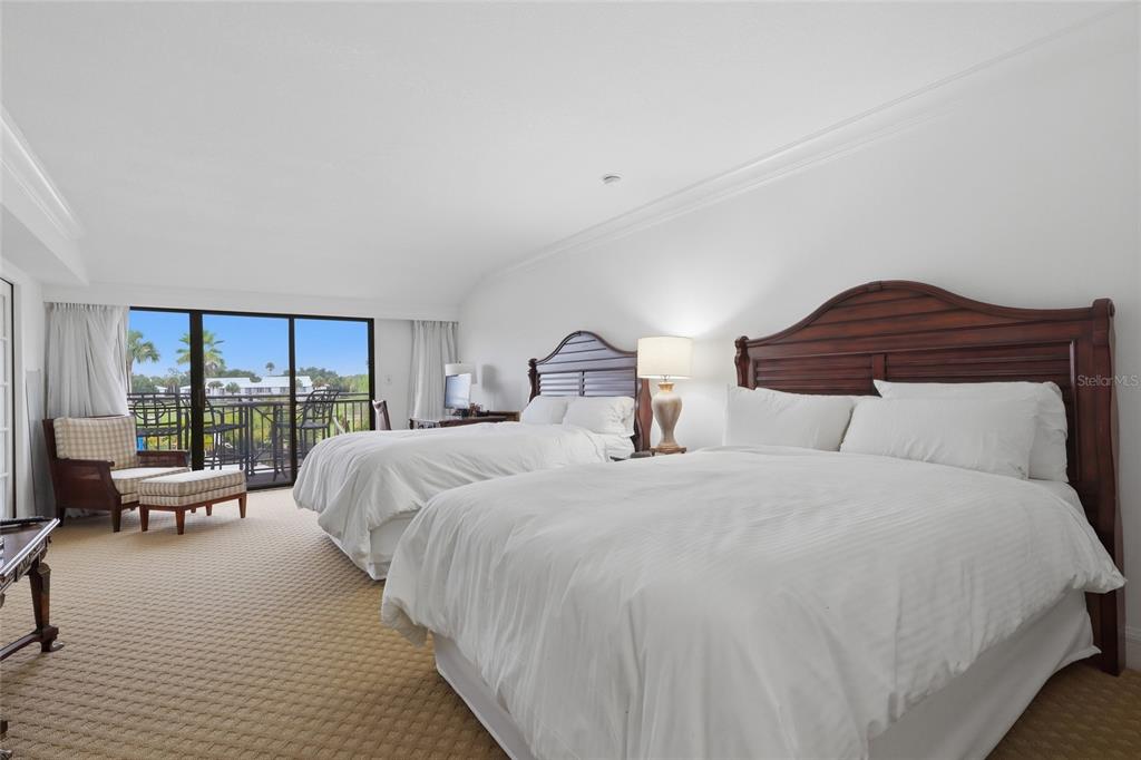 A bedroom features two beds, a seating area, and a balcony with an outdoor view — 29130 BAY HOLLOW DRIVE UNIT 3314, WESLEY CHAPEL, FL