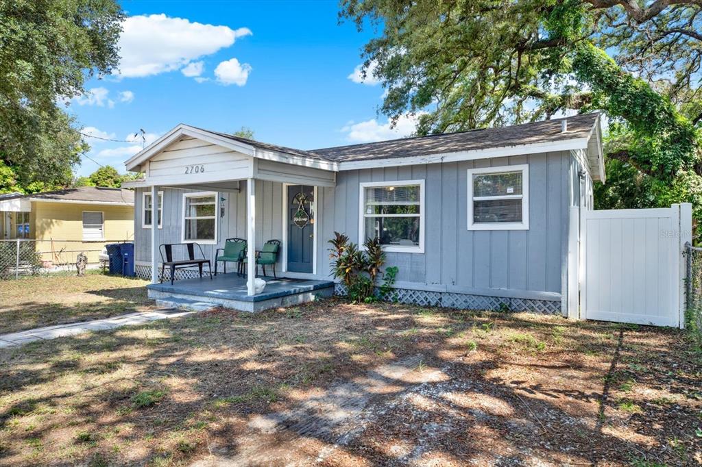 A single-story gray house with a front porch and a white privacy fence — 2706 E 22ND AVENUE, TAMPA, FL
