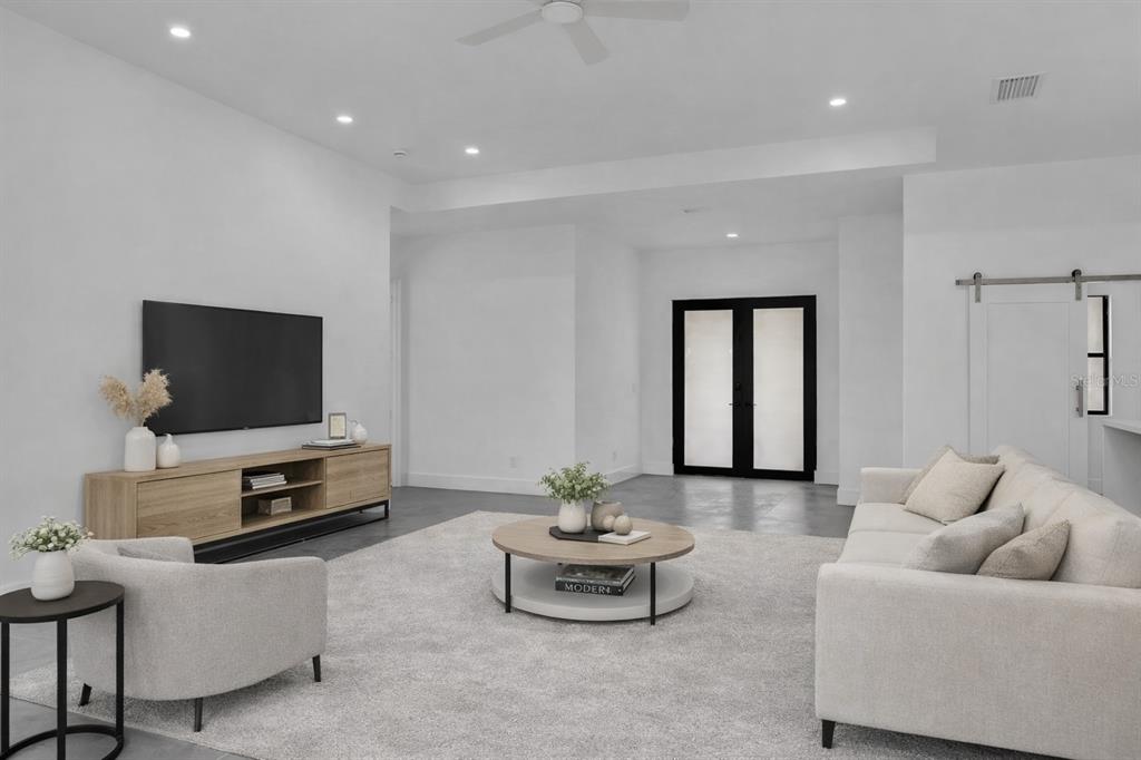 A modern living room features a white sofa, a circular coffee table, and a television console — 6191 KAMBACH STREET, PORT CHARLOTTE, FL