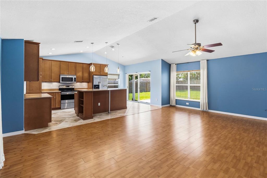 An open-concept kitchen and living area features wood flooring, blue walls, and a center island — 20446 MACON PARKWAY, ORLANDO, FL