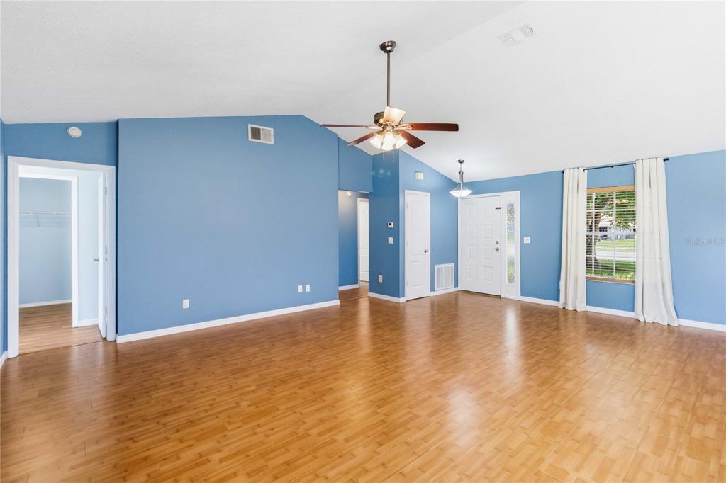 A living room with blue walls, wood-look flooring, a ceiling fan, and a front door — 20446 MACON PARKWAY, ORLANDO, FL