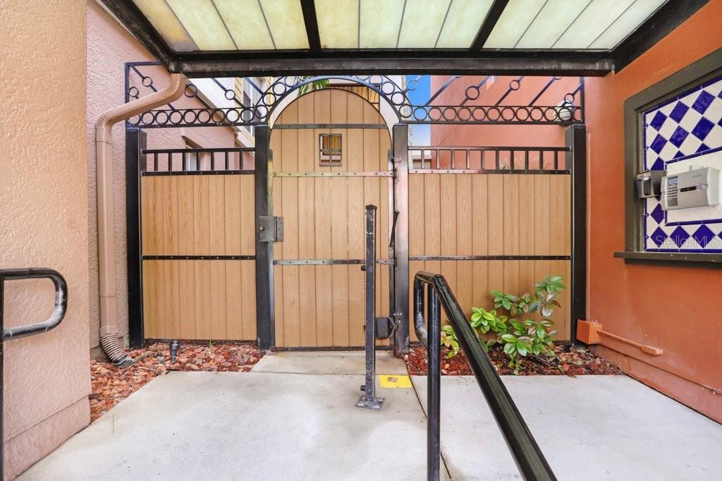 A gated courtyard entrance features a wooden door, metal fencing, and a covered walkway — 2440 W HORATIO STREET UNIT 1012, TAMPA, FL
