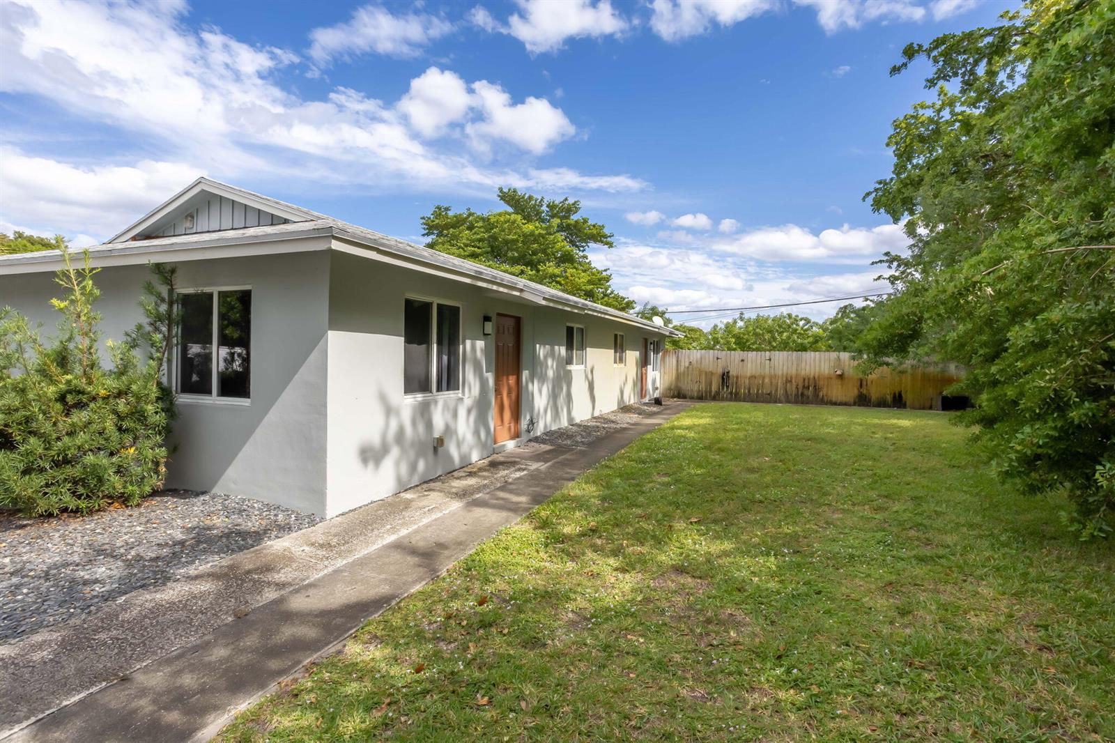 A single-story building with a concrete walkway, green lawn, and a wooden privacy fence — 2227 NE 3rd Avenue # 2, Delray Beach FL 33444, DELRAY BEACH, FL