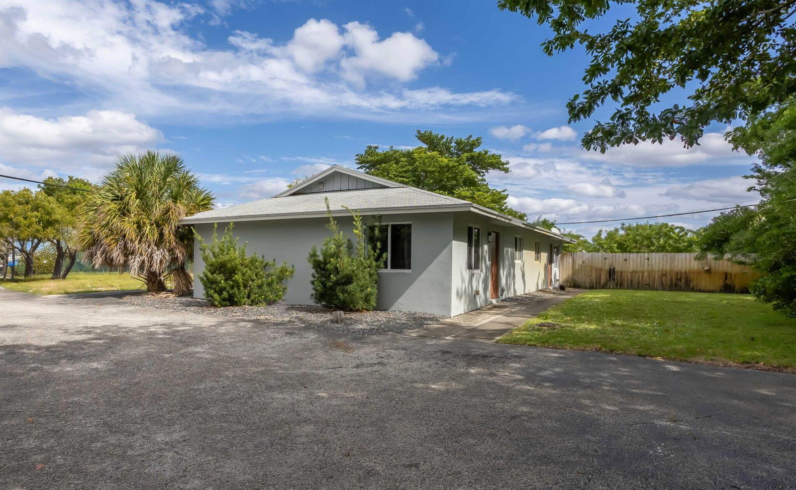 A single-story gray house with a gravel driveway and a fenced backyard under a blue sky — 2227 NE 3rd Avenue # 2, Delray Beach FL 33444, DELRAY BEACH, FL