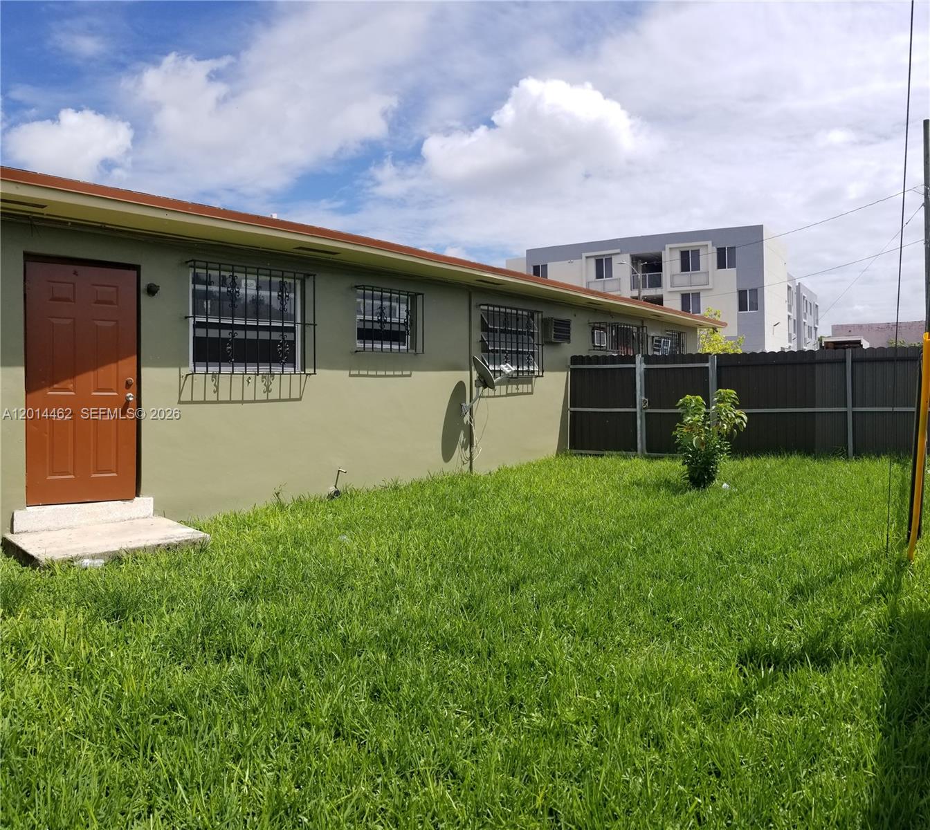 The exterior of a green house features a brown door and windows with security bars — 3210 NW 22nd Ave # 1, Miami FL 33142, MIAMI, FL