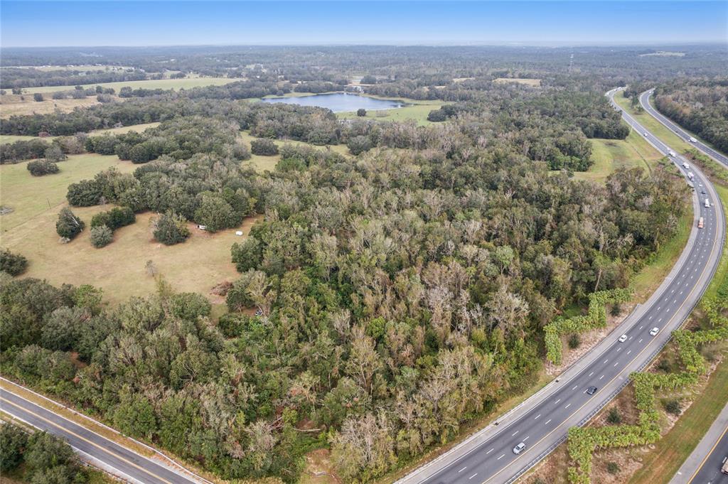 An aerial view shows a large, wooded plot of land bordered by two highways — 0 CHURCH ROAD, BROOKSVILLE, FL