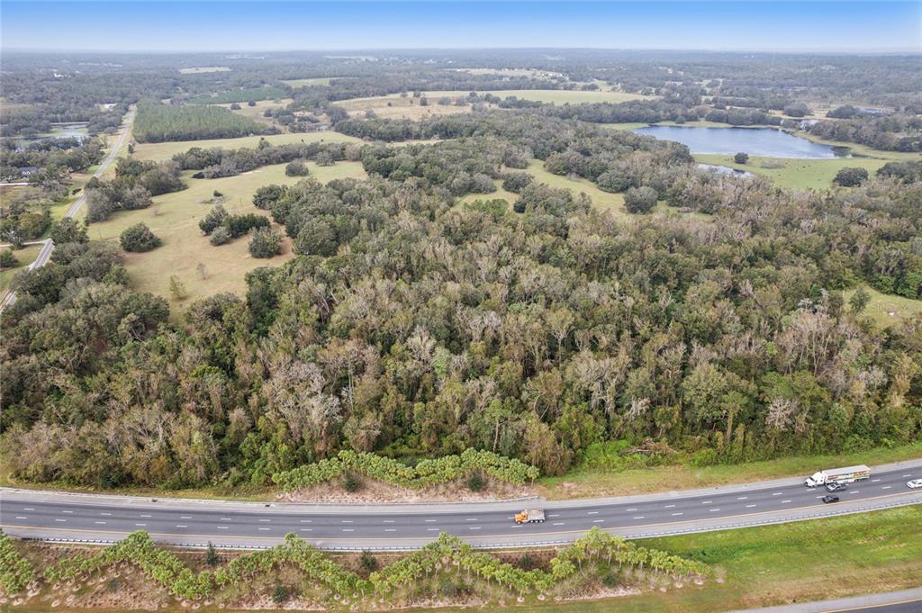 An aerial view shows a large, wooded plot of land bordering a multi-lane highway — 0 CHURCH ROAD, BROOKSVILLE, FL